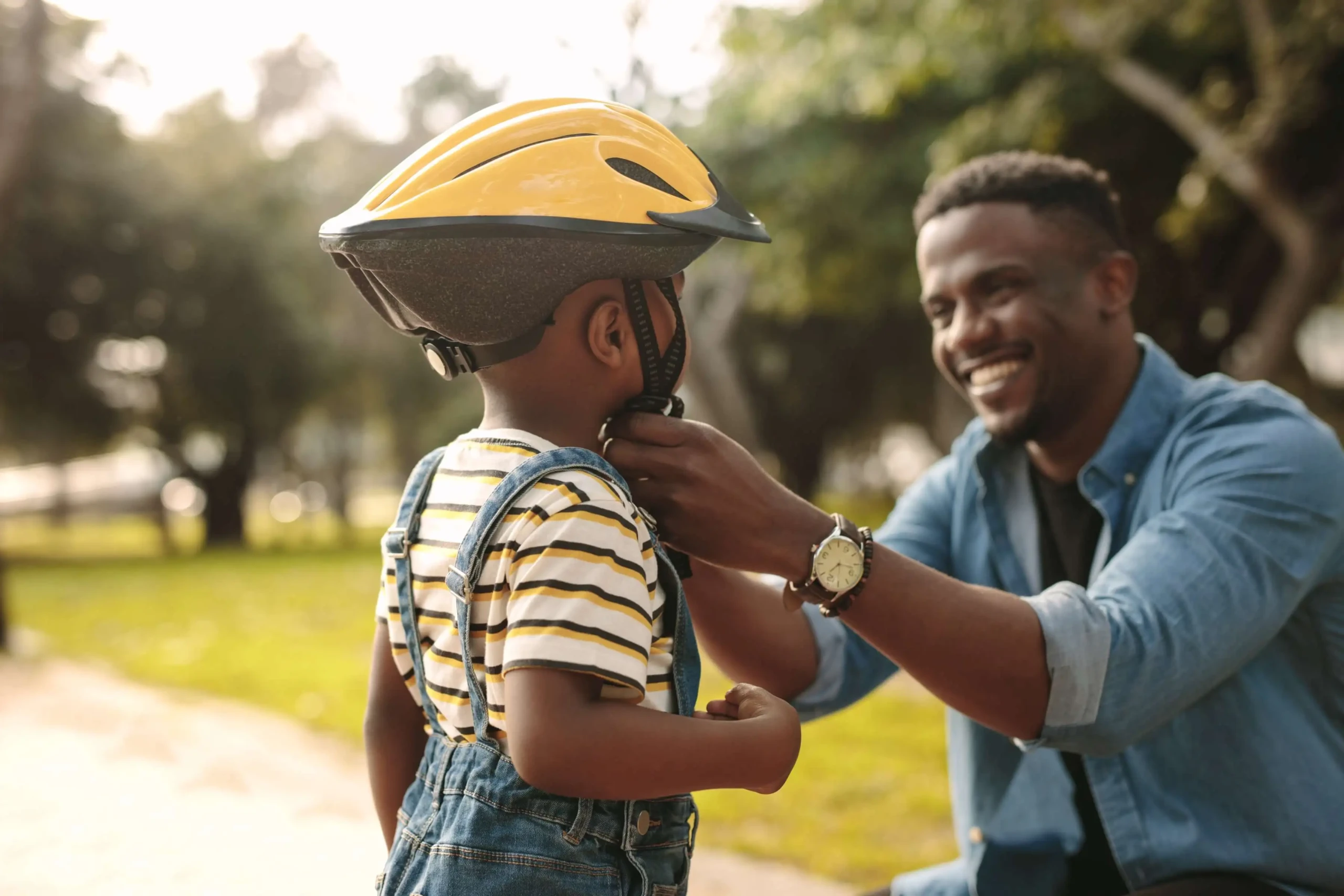 Man helps boy fasten helment learning how to ride a bike