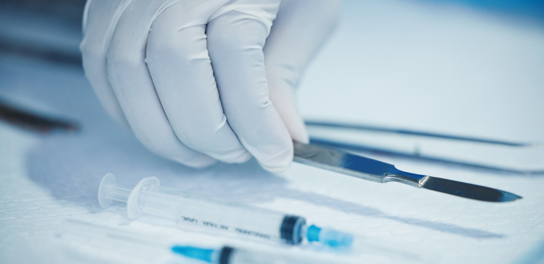 A doctor's gloved hand holding a scalpel, indicating defective medical device lawsuits.