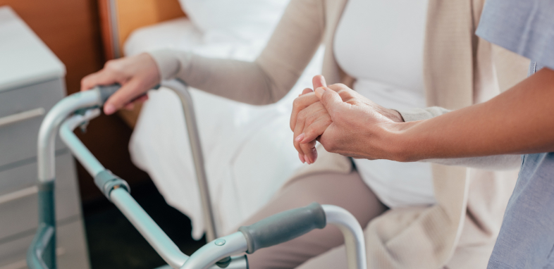 Elderly person being helped off the edge of a bed, representing nursing home abuse.