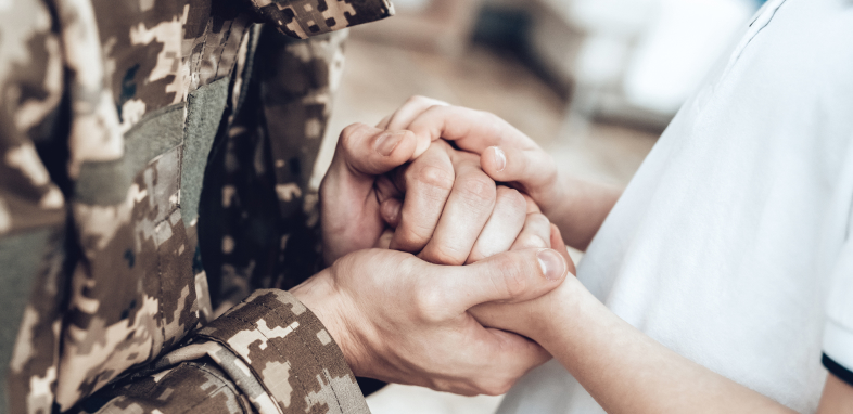 A person in uniform holding hands with their spouse, representing veteran disability cases.