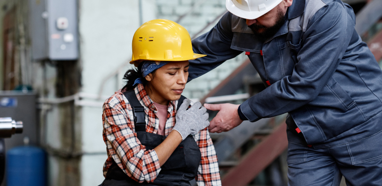 Worker holding her shoulder in pain, indicating workers' compensation claims.